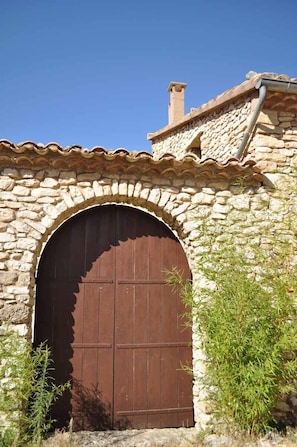 Traditional stone building with an arched entrance and a large wooden door.