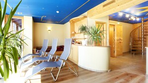 Un interior moderno con techo azul, pisos de madera y una zona de estar central con sillones.