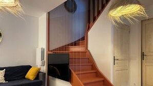 Un salon moderne doté d’un escalier à volutes, d’un téléviseur à écran plat fixé au mur, d’une table basse en bois et d’un canapé agrémenté de coussins.