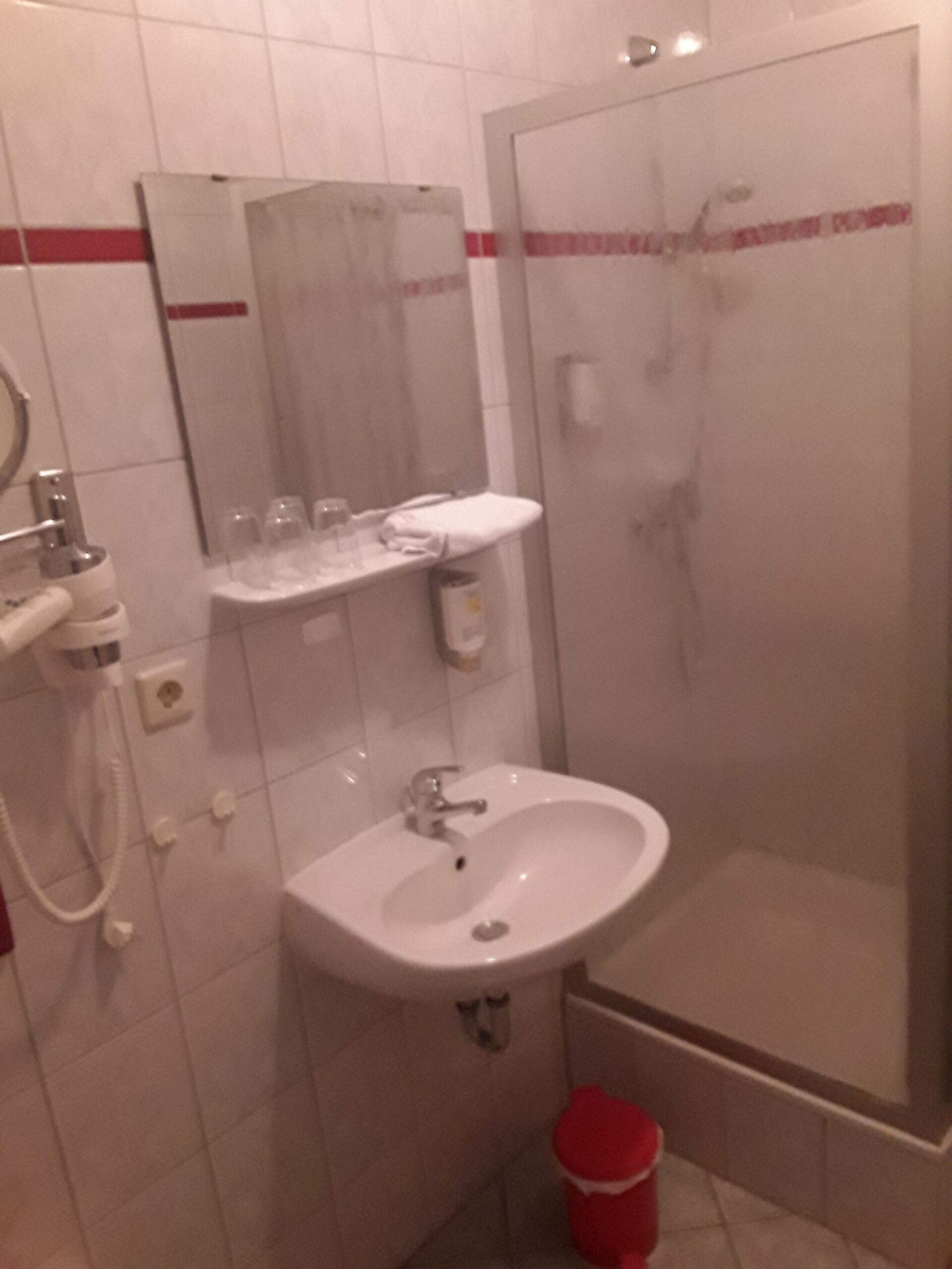 A bathroom with a sink, mirror, and shower.