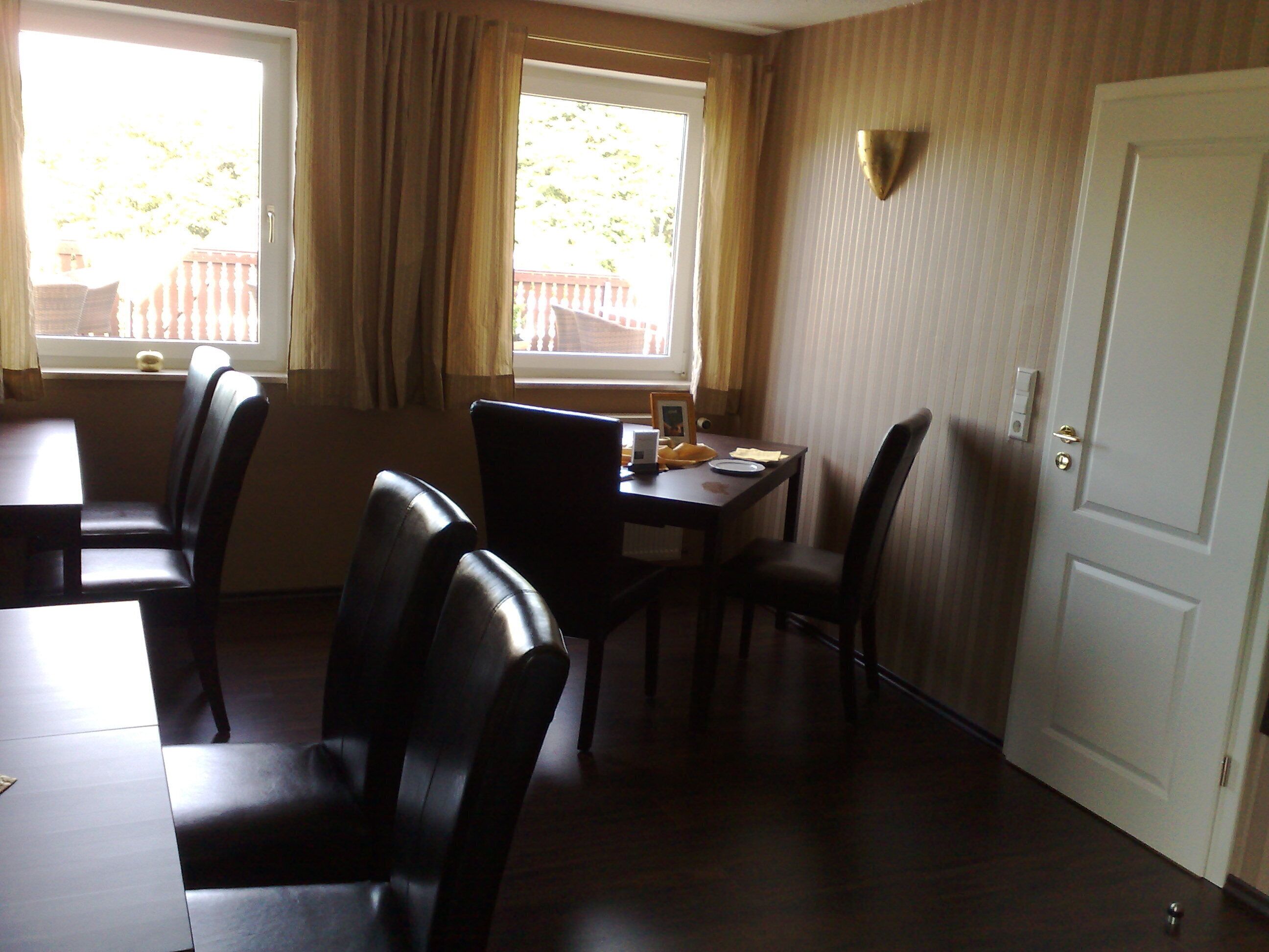 Un comedor con una mesa y sillas, una ventana con cortinas y una puerta.