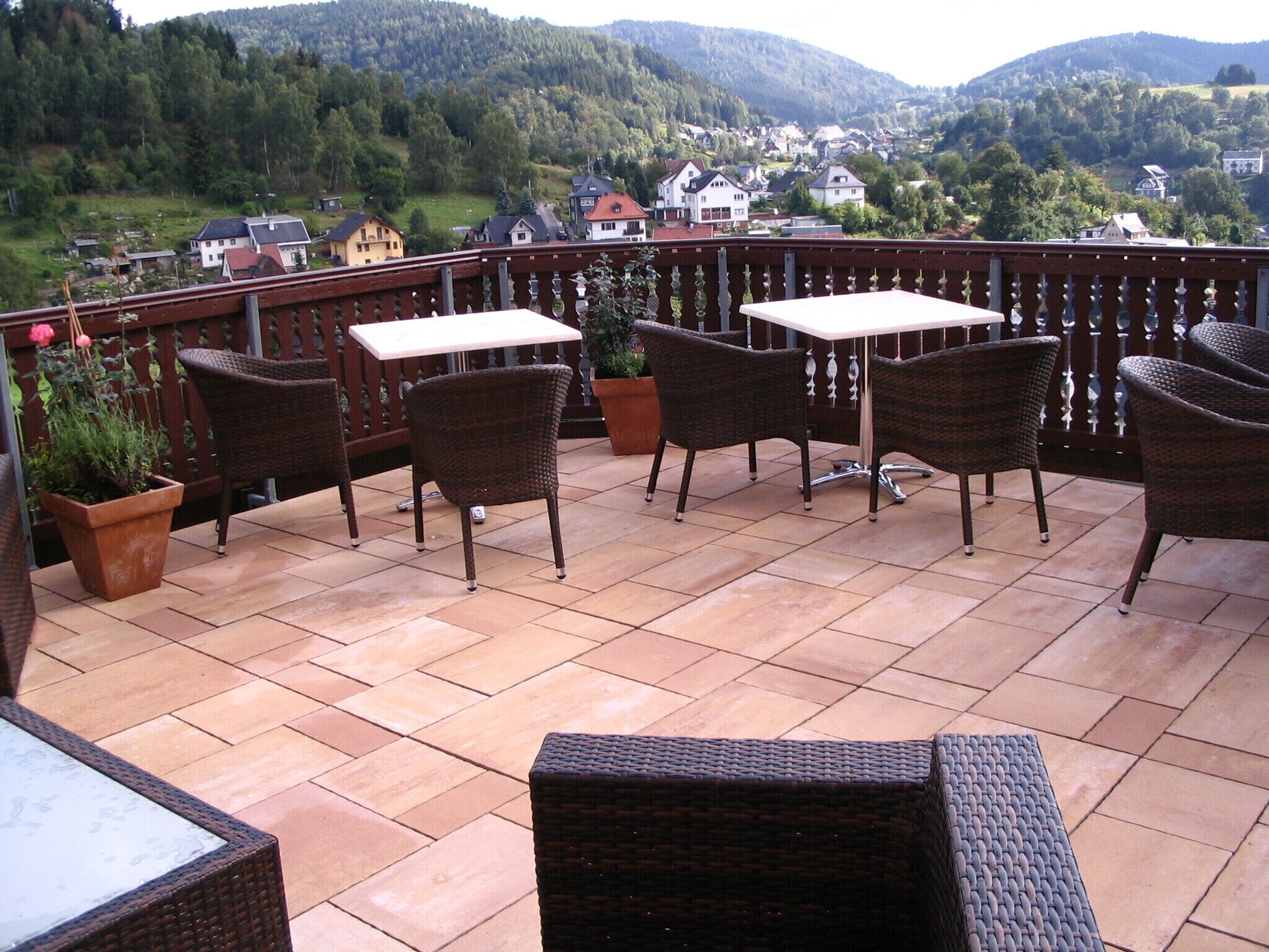 A terrace with wicker furniture, a table, and potted plants.