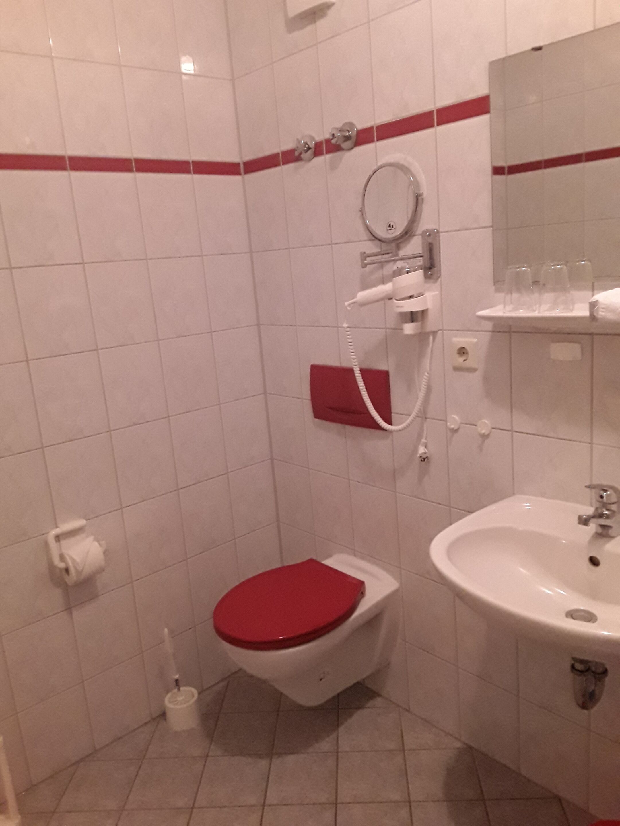 A bathroom with a white sink, a red toilet, and a mirror above the sink.