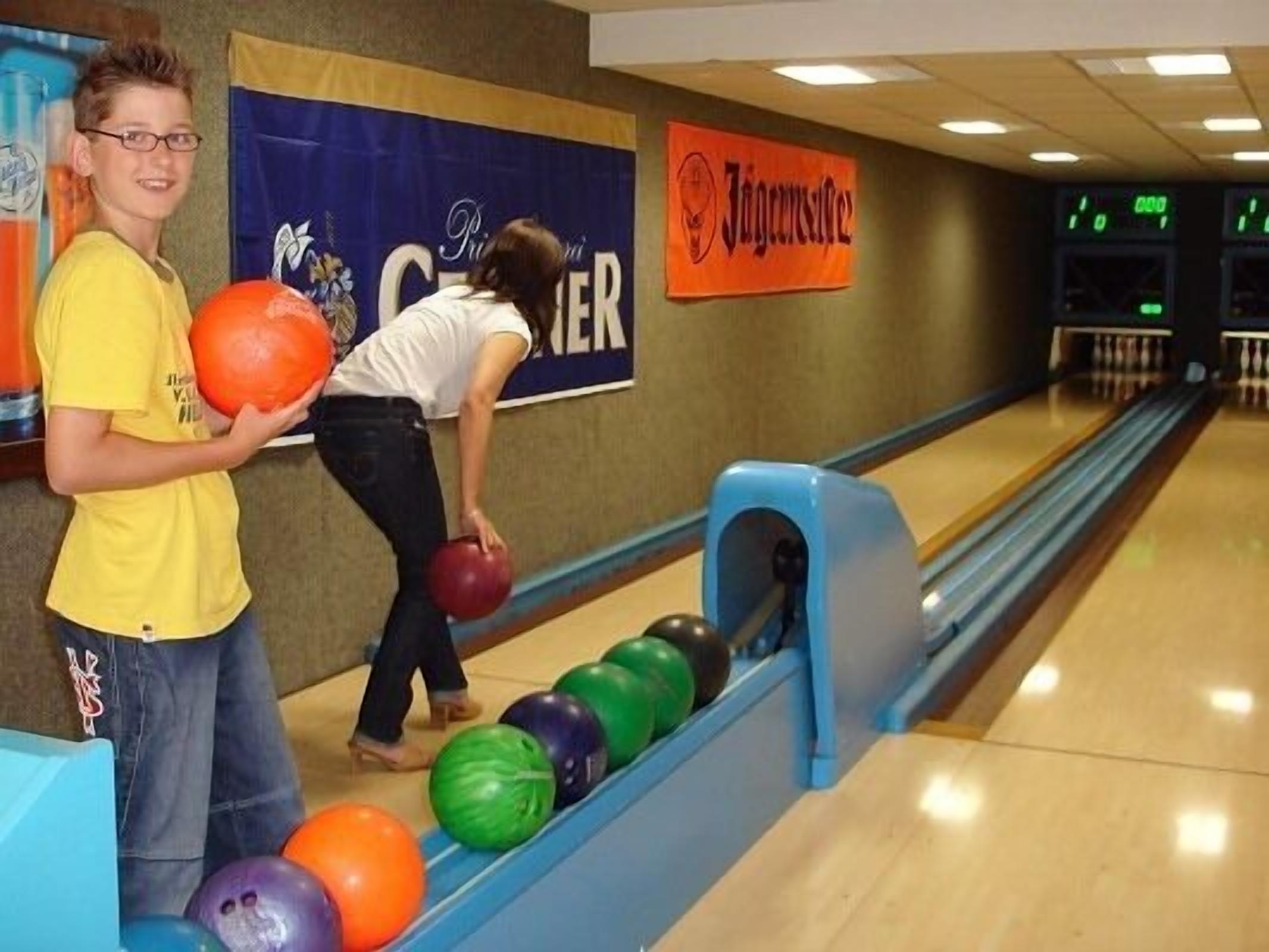 A bowling alley with lanes, a bowling ball, and a person preparing to bowl.
