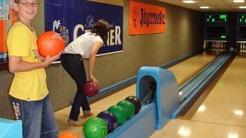 A bowling alley with lanes, a bowling ball, and a person preparing to bowl.