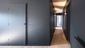 A modern hallway with dark walls and a wooden floor, leading to a door. - To complete (Saint-Cast-le-Guildo)