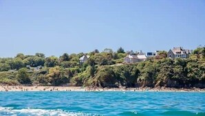 A coastal view with houses on a hillside, a beach with people, and clear blue water. - To complete (Saint-Cast-le-Guildo)