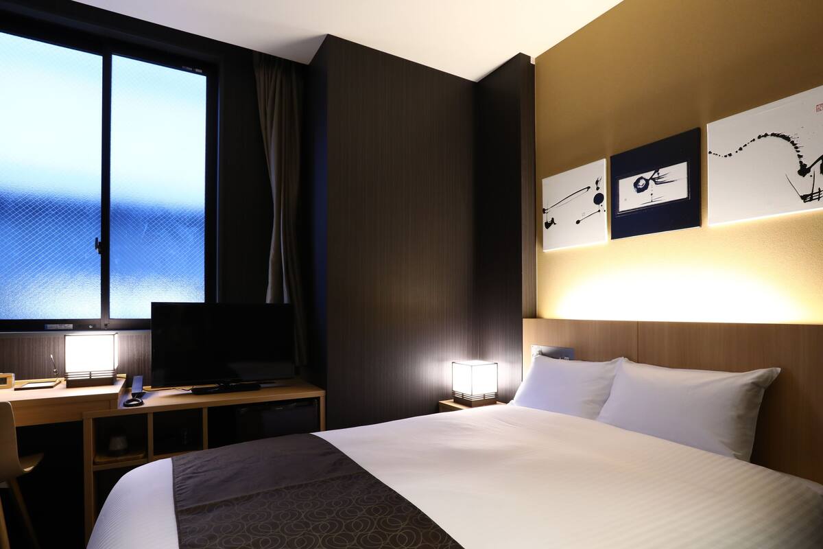 Ein Hotelzimmer mit einem Bett, einem Schreibtisch mit Computer, einem Fernseher und einem Fenster mit Meerblick.