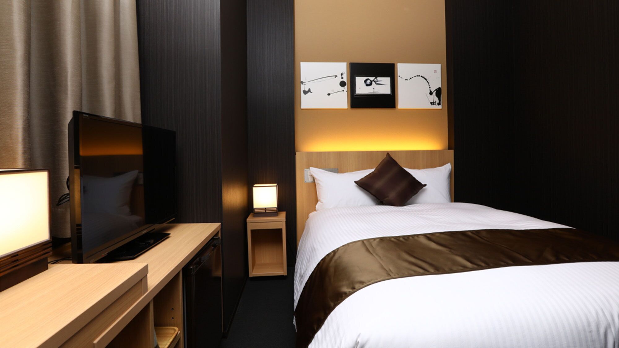 Een hotelkamer met een bed, een televisie, een bureau en een nachtkastje.