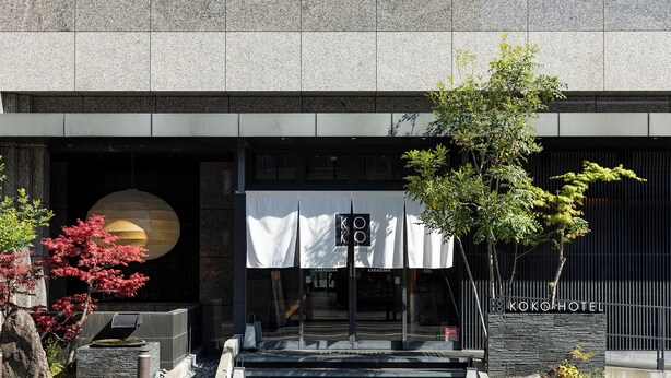 Un edificio moderno con un letrero que dice 'KOKOHOTEL' y una gran estructura esférica a la izquierda.