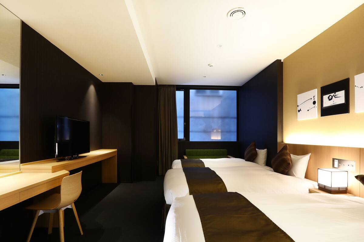 Ein Hotelzimmer mit Bett, Schreibtisch, Fernseher und Fenster.