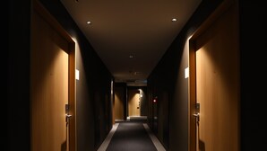 Un pasillo de hotel con puertas de madera, pisos alfombrados e iluminación empotrada en el techo.
