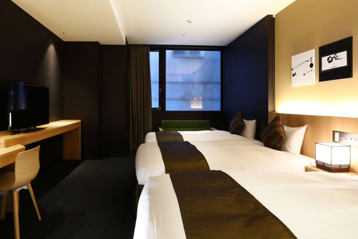Ein Hotelzimmer mit Bett, Schreibtisch, Stuhl, Fernseher und Fenster.