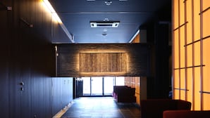 Un pasillo con taquillas, un panel de pared de madera y zonas de estar rojas.