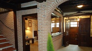 Een ruime kamer met een schouw van baksteen, een houten trap en een kleine potplant.