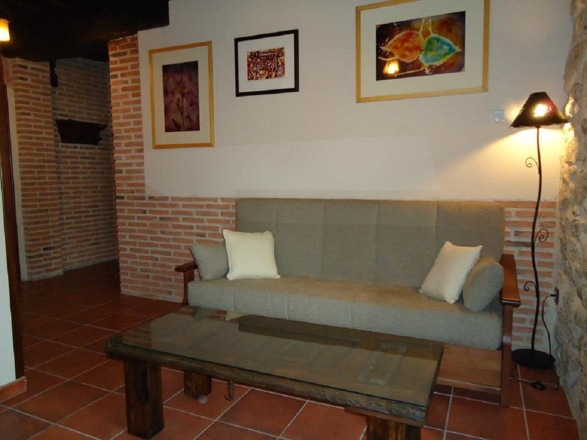 A living room with a sofa, a glass coffee table, and a lamp.