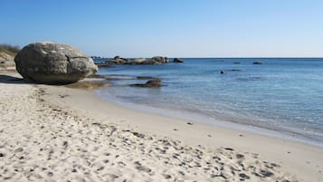 Une plage de sable avec de gros rochers et une eau calme.