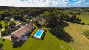 Vista aérea de uma propriedade campestre com piscina, várias casas e vegetação ao redor.