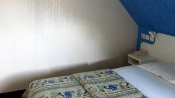 A bedroom with a bed, a nightstand, a TV mounted on the wall, and a blue accent wall.