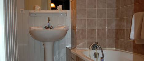 Un baño con lavamanos, inodoro y bañera blancos.