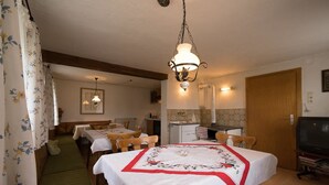 A dining area with a table set for two, a hanging light fixture, and a television in the corner. - Haus am Waldesrand (Regen)