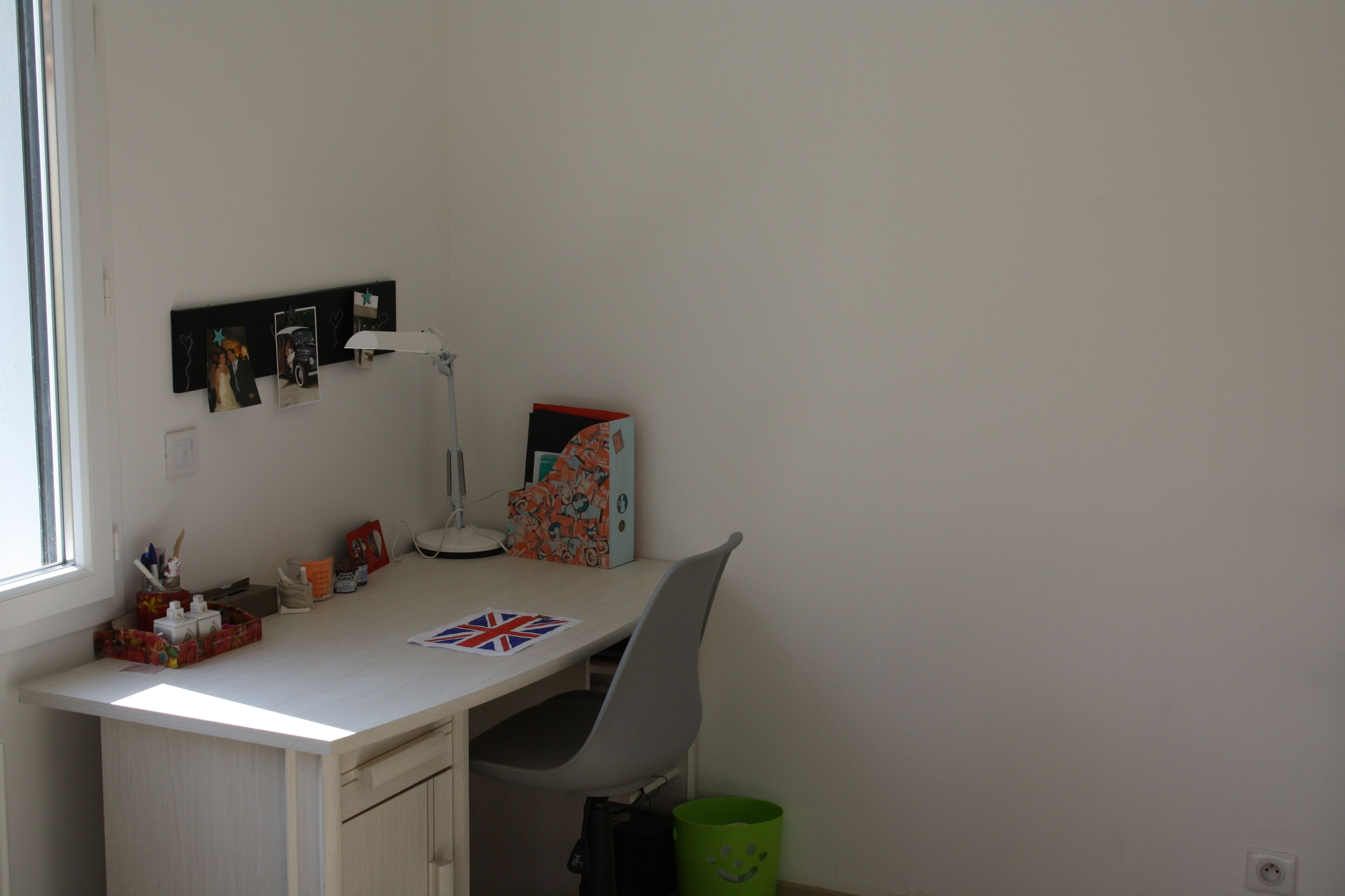 Un espacio de trabajo pequeño y ordenado, con escritorio, silla y varios objetos personales.