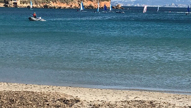 Paisaje costero con una playa de arena y acantilados rocosos.
