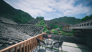 A traditional courtyard with tiled roofs, a wooden railing, and a table with chairs. - Stay in joy Boutique Inn (Qiandongnan)