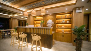 A bar area with wooden stools, a counter, and hanging lights. - Stay in joy Boutique Inn (Qiandongnan)