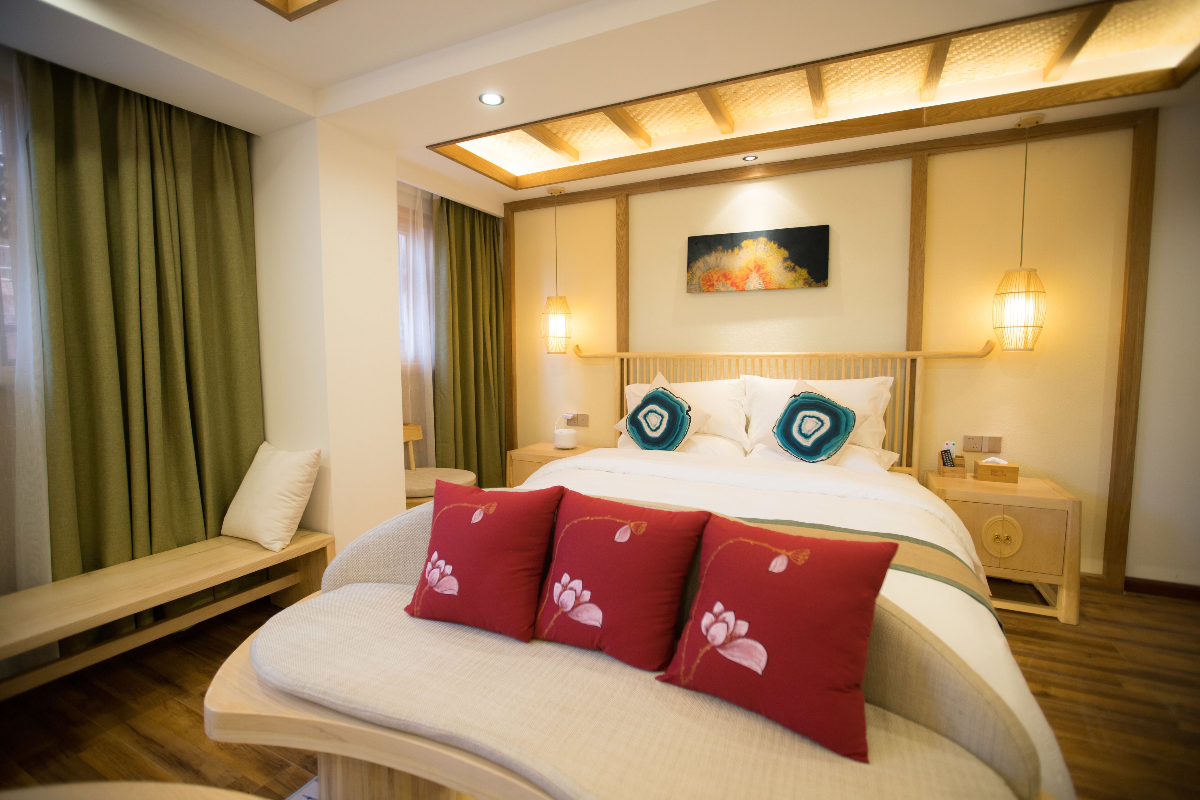 A hotel room with a large bed, two bedside tables, a bench, and a painting on the wall.