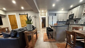 A modern kitchen with white cabinets, a microwave, and a sink. There is a dining area with a wooden table and chairs. - Luxury Remodel Downtown Condo Across from Yampa River 
CANNOT BEAT THE LOCATION! (Steamboat Springs)