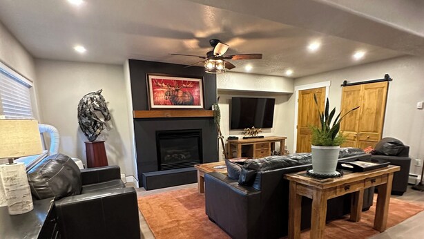 A modern living room with a fireplace, leather sofas, a coffee table, and a ceiling fan. - Luxury Remodel Downtown Condo Across from Yampa River 
CANNOT BEAT THE LOCATION! (Steamboat Springs)