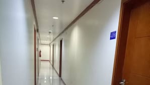 Un passadís llarg i estret amb parets blanques i un sòl de rajoles brillants. Hi ha portes a la dreta, una de les quals té un senyal amb el número 409.