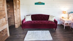 Una habitación con pared de madera, un sofá de terciopelo rojo, una alfombra blanca y un letrero que dice 'WELCOME'.