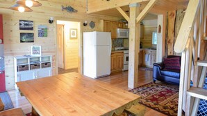 A wooden interior with a kitchen area, a dining table, and a sofa. - Beachfront property located on Resurrection Bay! (Lowell Point)