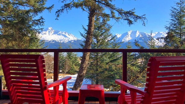 A deck with red chairs and a table, overlooking a snowy mountain range. - Beachfront property located on Resurrection Bay! (Lowell Point)