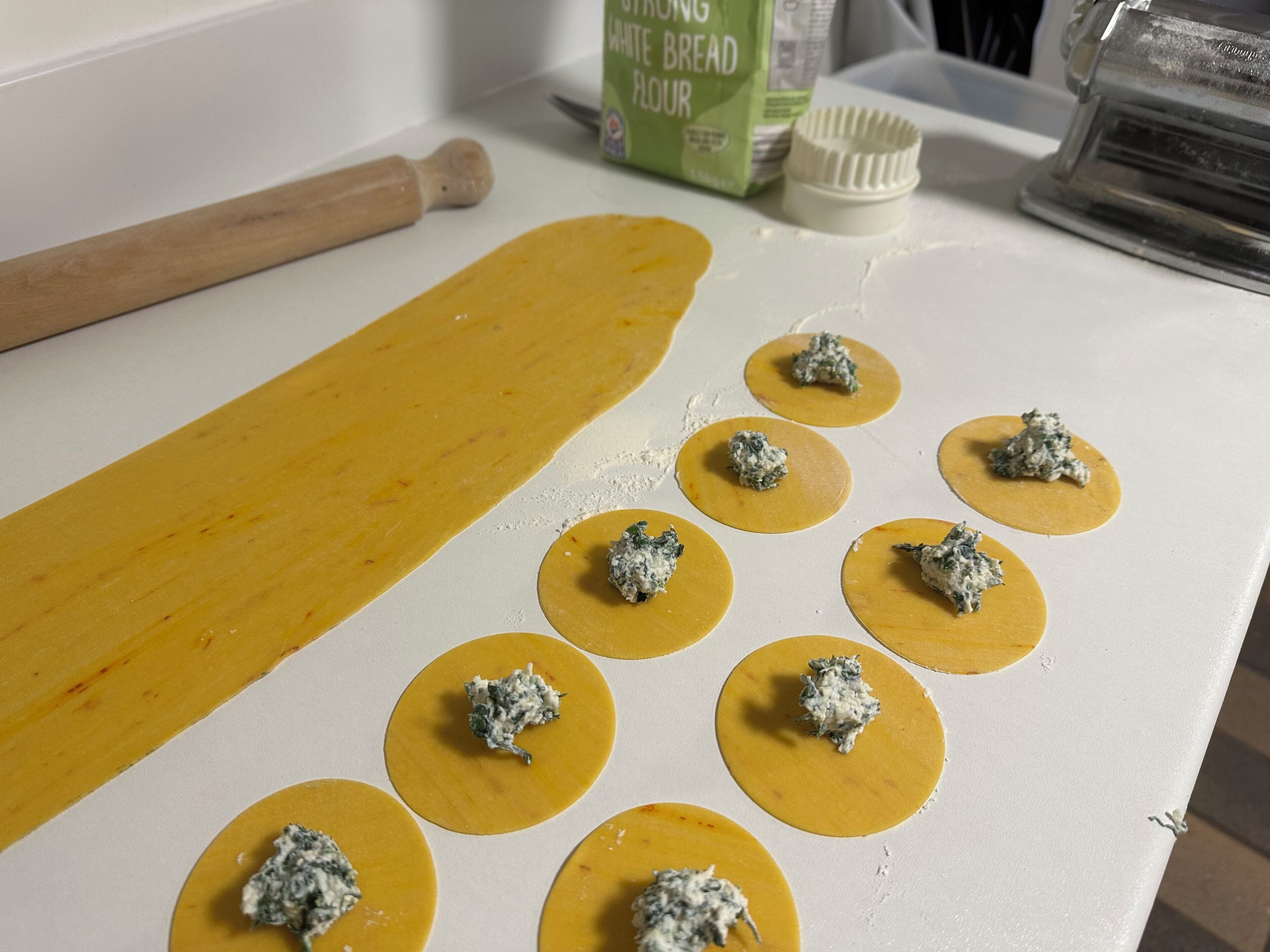 Una encimera de cocina con círculos de masa y un rodillo.