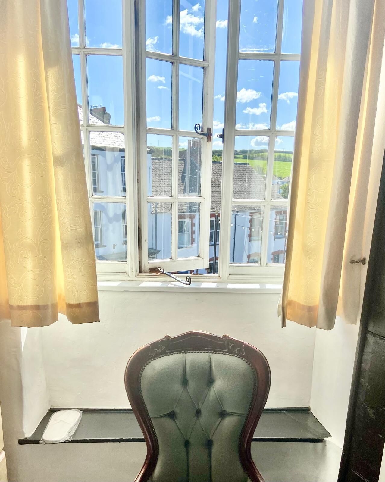 Een kamer met een groot raam, een stoel en een scooter voor de deur.
