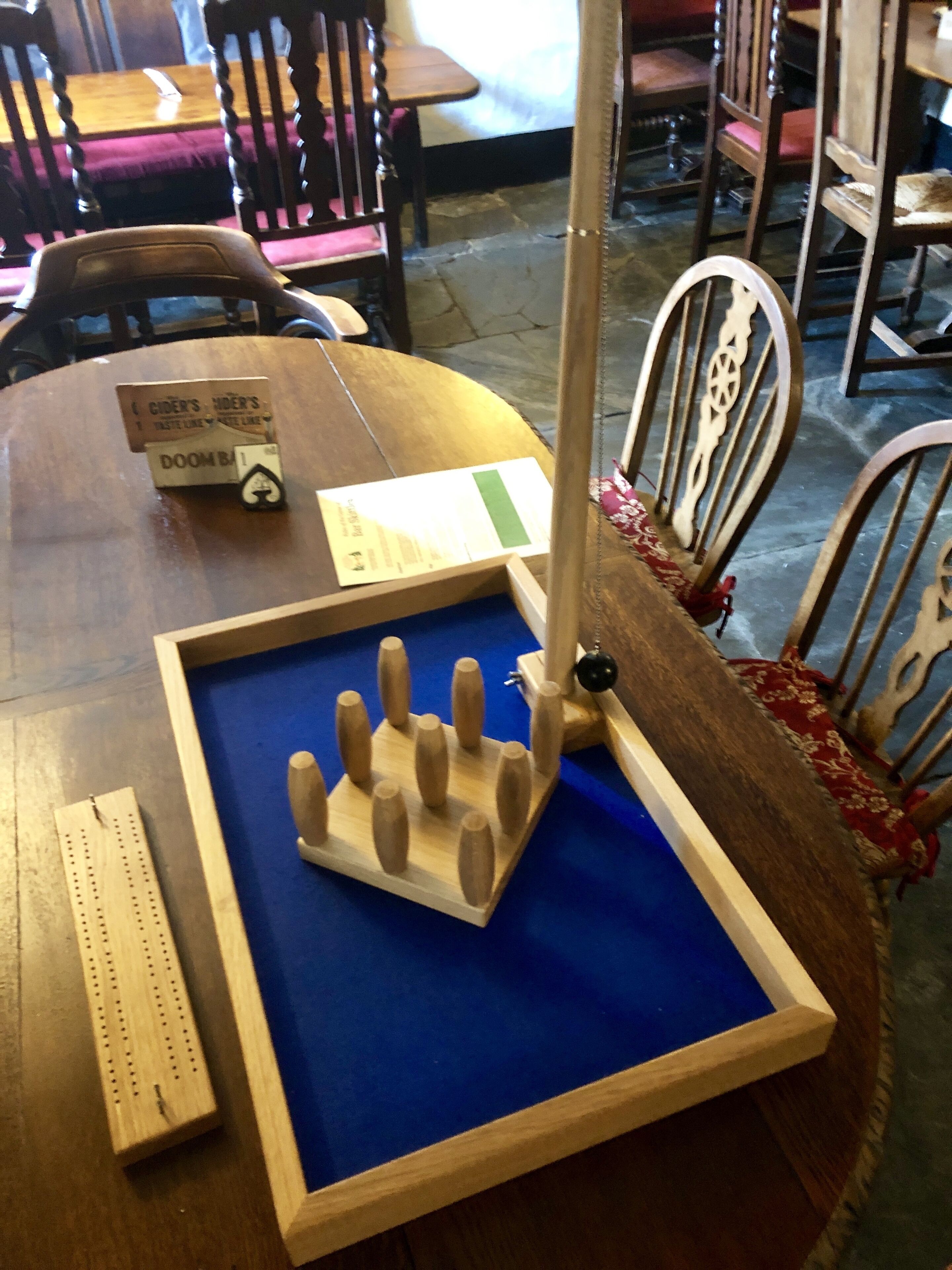 Een houten tafel met een blauwe tafelkleed, een houten voetstuk met een zwarte knop, en een wit bord met tekst.
