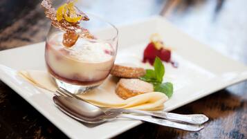Un postre con un recipiente de vidrio, una cuchara y un plato sobre una mesa de madera.