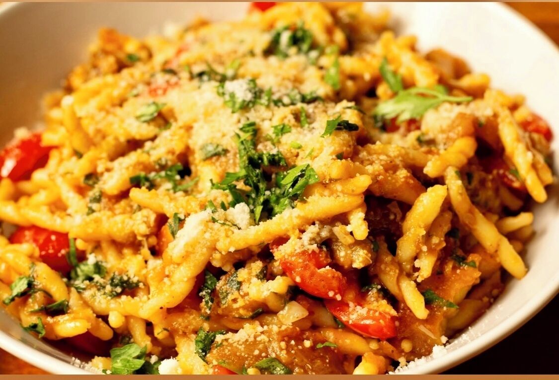 A bowl of pasta with vegetables and cheese.