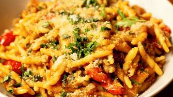 A bowl of pasta with vegetables and cheese.