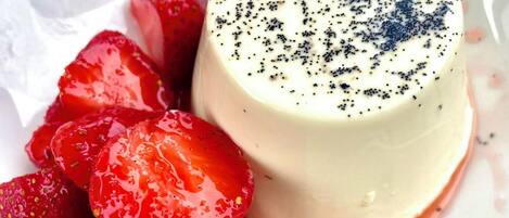 Une panna cotta, dessert à base de crème, servie avec des fraises et nappée d’une sauce.