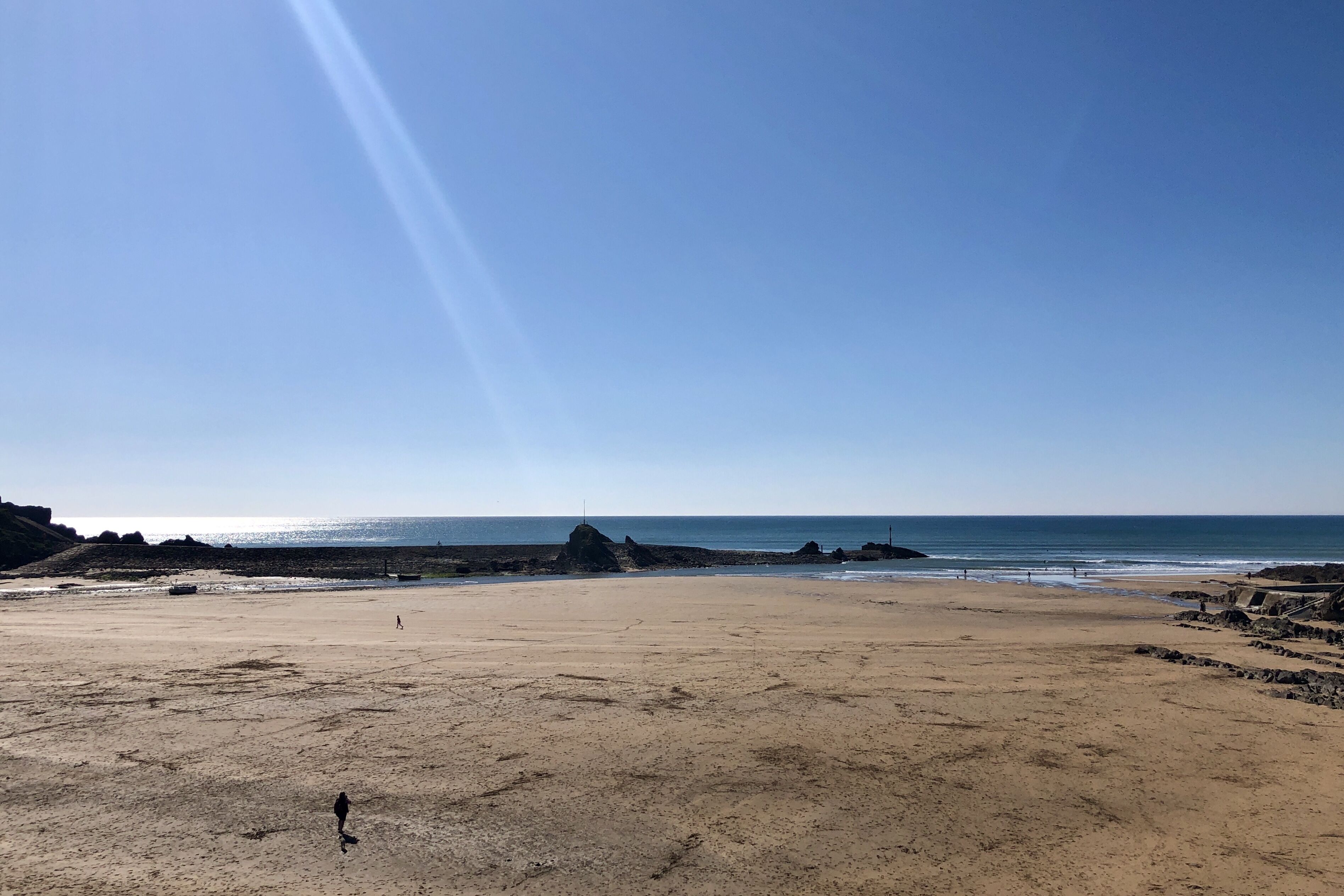 A wide sandy beach with a clear sky and calm sea.