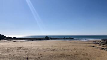 Ein weiter Sandstrand mit blauem Himmel und ruhiger See.