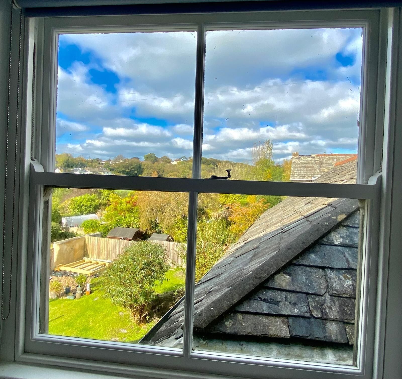 A window with a view of a garden and a stone structure.