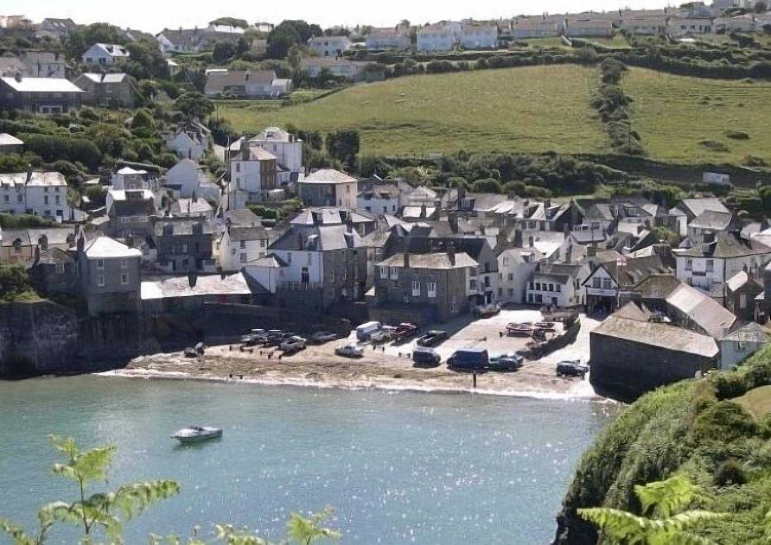 A coastal town with historic stone buildings, a sandy beach, and a calm sea.