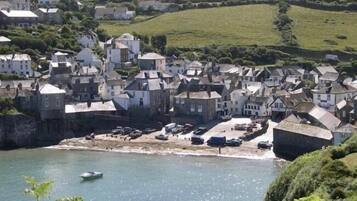 A coastal town with historic stone buildings, a sandy beach, and a calm sea.