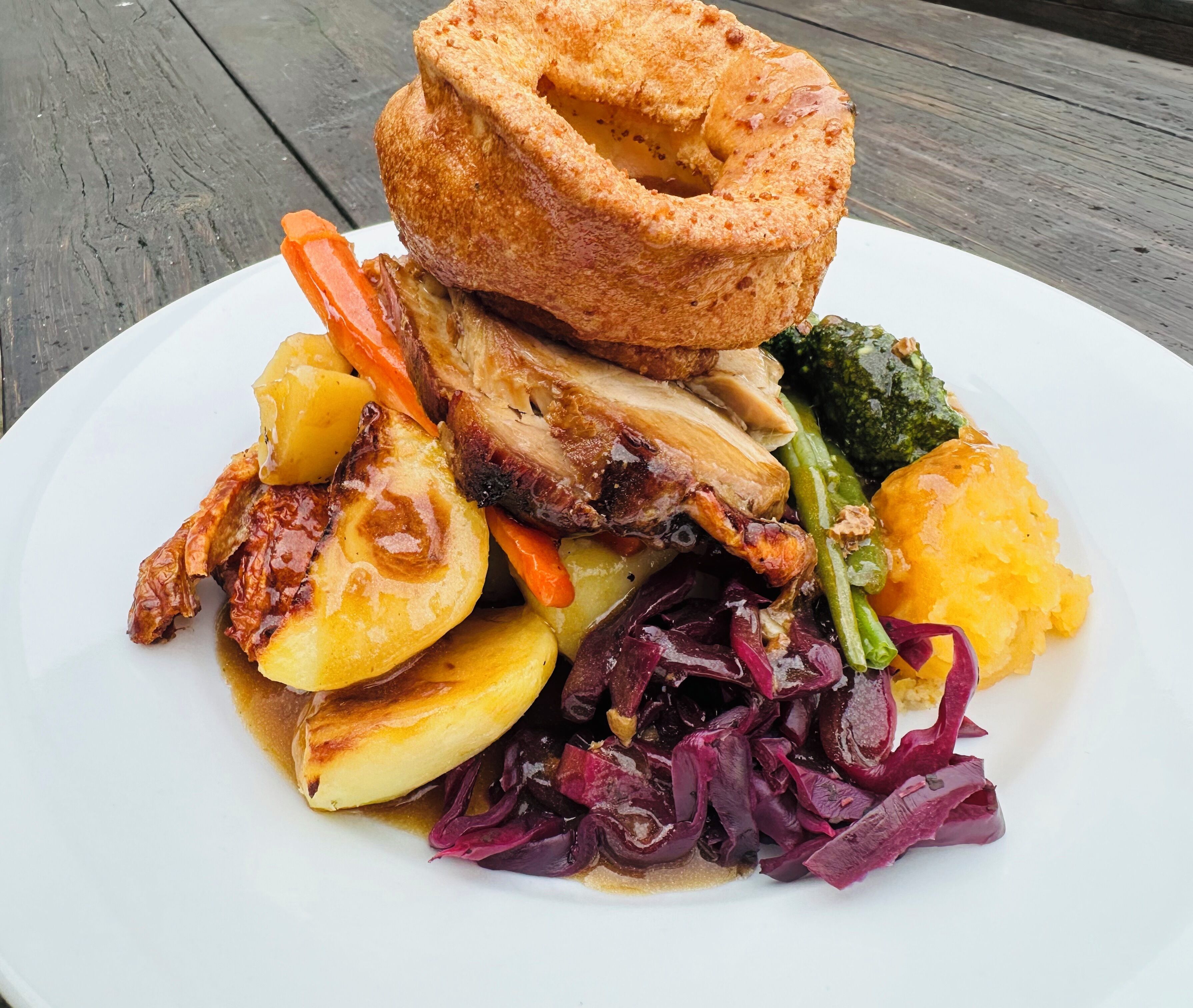 A plate of food with roasted meat, vegetables, and Yorkshire pudding.