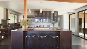 A modern kitchen with a central island, bar stools, pendant lighting, and dark cabinetry. - Private Wine Country Estate with Panoramic Views, Tennis Court - TOT Cert 450N (Kenwood)